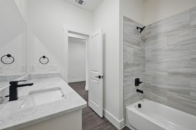 Full bathroom with tub / shower combination, a sink, visible vents, double vanity, and wood finished floors | Image 15