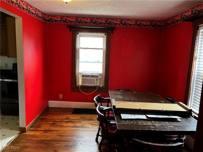 Dining room featuring cooling unit, a textured ceiling, wood finished floors, and baseboards | Image 8