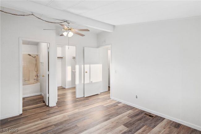 Primary bedroom with vaulted ceiling with beams, wood style floors, and baseboards | Image 21