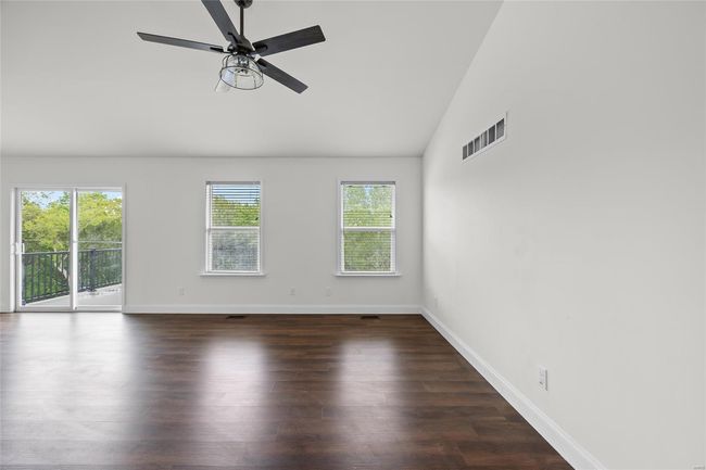 Unfurnished room featuring visible vents, wood finished floors, lofted ceiling, baseboards, and ceiling fan | Image 22