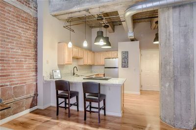 Kitchen featuring stainless steel refrigerator, a high ceiling, kitchen peninsula, sink, and light hardwood / wood-style floors | Image 2