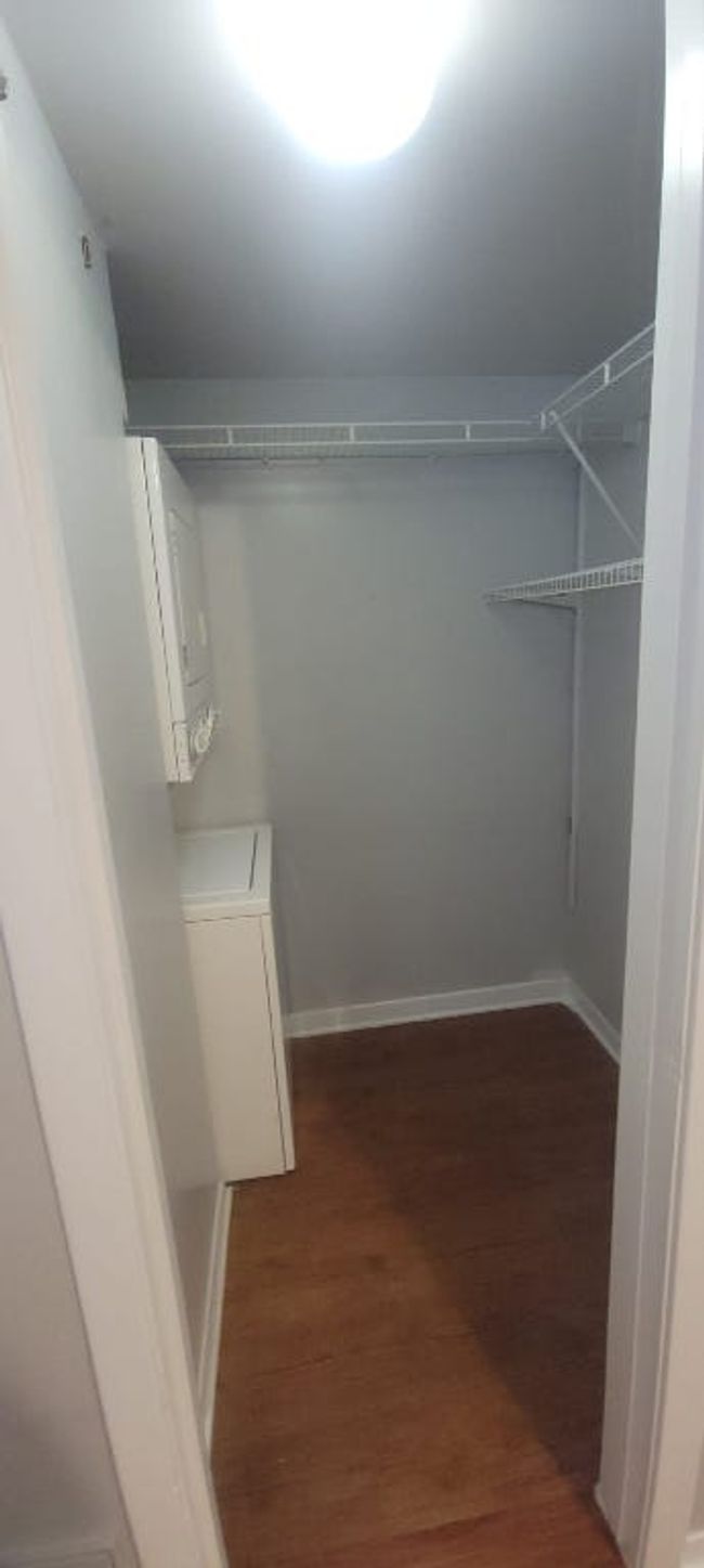 Spacious closet featuring stacked washer / dryer and wood finished floors | Image 8