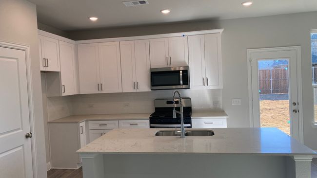 Kitchen with stainless steel appliances, white cabinetry, decorative backsplash, and recessed lighting | Image 4