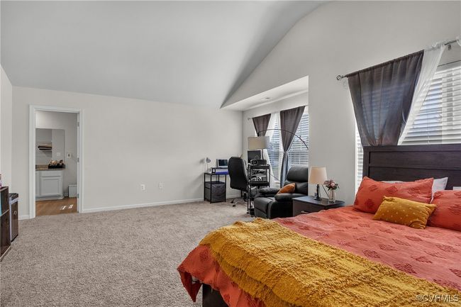 Carpeted bedroom with baseboards, lofted ceiling, and connected bathroom | Image 10
