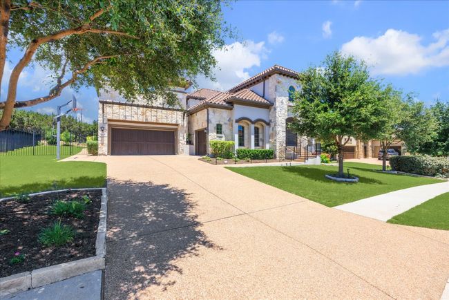 Mediterranean / spanish-style home featuring a tile roof, a front yard, stone siding, concrete driveway, and fence | Image 38