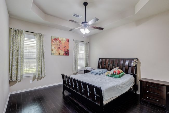 Bedroom featuring baseboards, dark wood-style floors, a tray ceiling, and a ceiling fan | Image 24