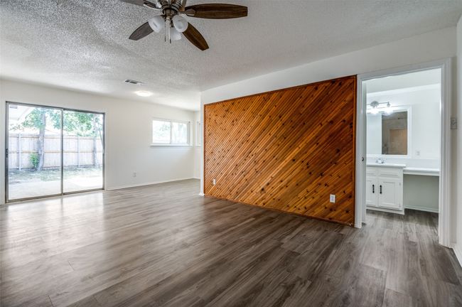 Unfurnished room with ceiling fan, dark wood finished floors, wood walls, and a textured ceiling | Image 12