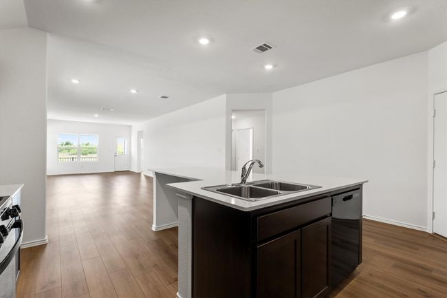 Kitchen with dishwasher, dark wood-style floors, light countertops, a kitchen island with sink, and recessed lighting | Image 9