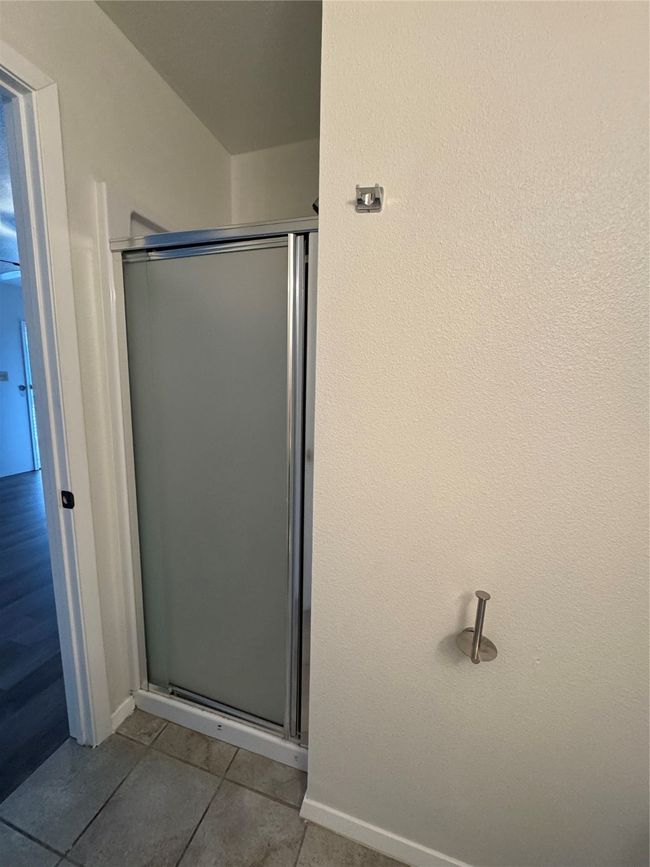 Bathroom with a stall shower, tile patterned flooring, and baseboards | Image 21