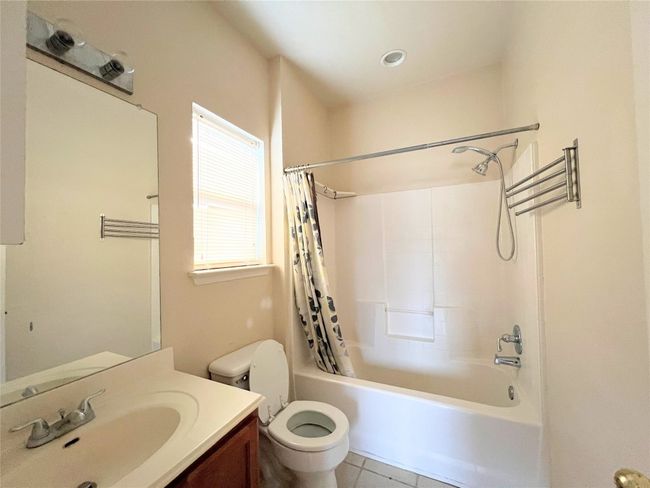 Bathroom featuring toilet, shower / tub combo with curtain, vanity, and tile patterned floors | Image 7