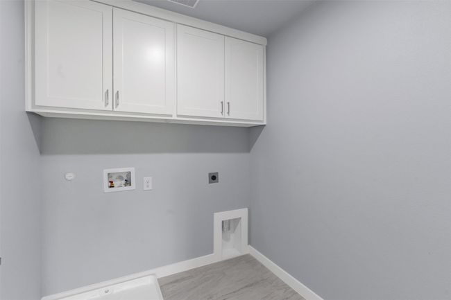 Laundry area featuring hookup for an electric dryer, gas dryer hookup, cabinet space, and hookup for a washing machine | Image 24