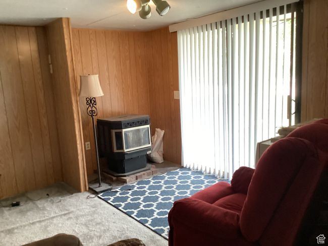 Living area with wooden walls, a wood stove, and carpet | Image 10