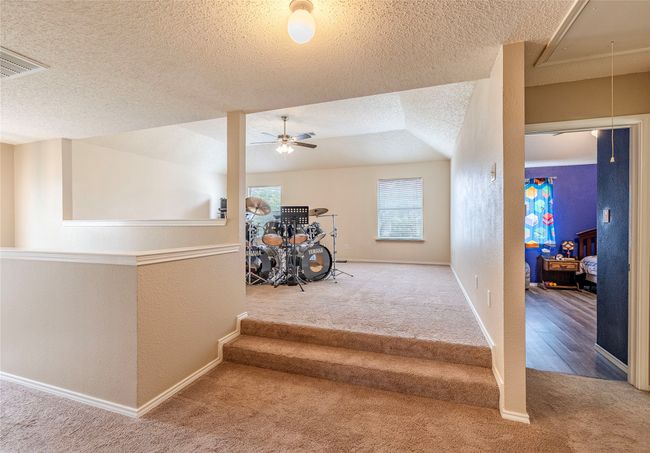 Stairway featuring carpet flooring, attic access, a textured ceiling, a ceiling fan, and a textured wall | Image 25