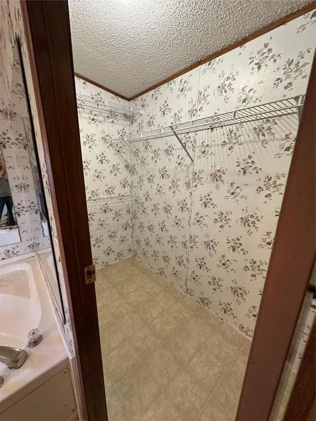 Bathroom with a textured ceiling, ornamental molding, and wallpapered walls | Image 24