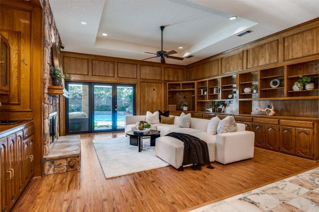 Living area featuring a raised ceiling, light wood finished floors, a fireplace, recessed lighting, and ceiling fan | Image 4