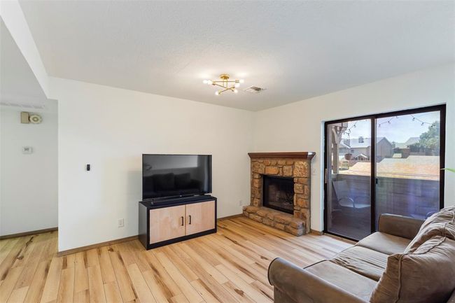 Living room with light wood-type flooring, a stone fireplace, and a chandelier | Image 8