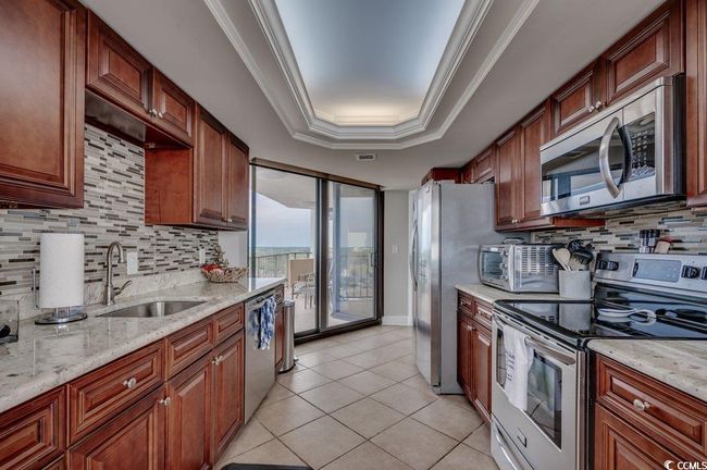 Kitchen featuring light stone counters, stainless steel appliances, and decorative backsplash | Image 9