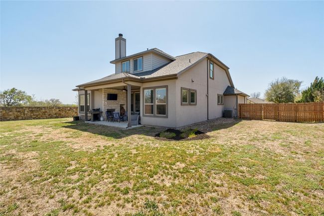 Rear view of house featuring a fenced backyard, a chimney, a yard, and a patio area | Image 29