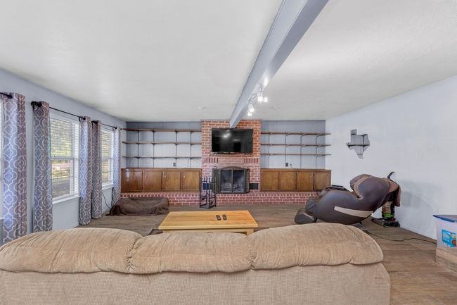 Living room featuring wood finished floors, beamed ceiling, and a brick fireplace | Image 19