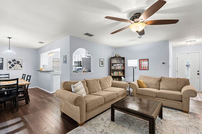 Living room with wood finished floors, ceiling fan, and baseboards | Image 8