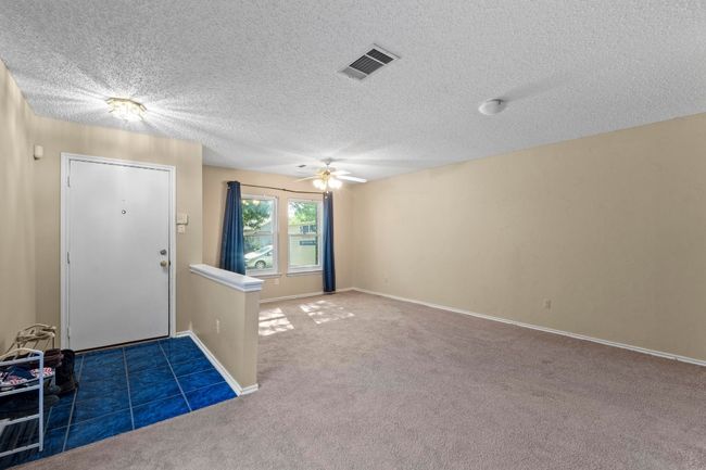 Carpeted entrance foyer with a ceiling fan, a textured ceiling, and baseboards | Image 4