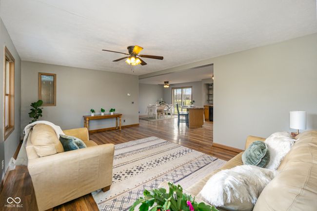 living area with baseboards, wood finished floors, and a ceiling fan | Image 11