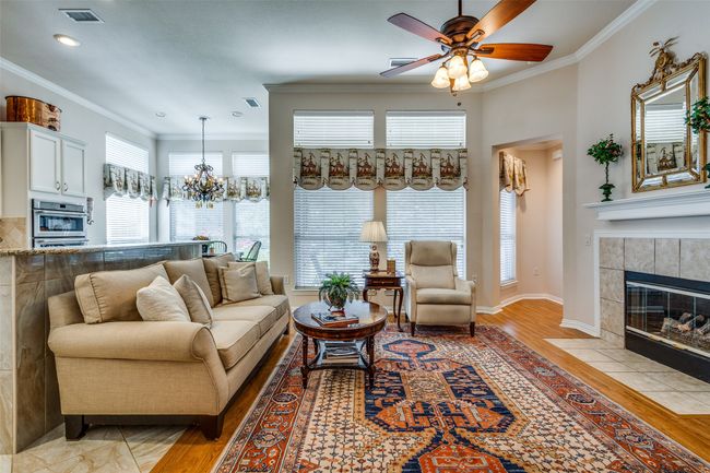 Living room with a tiled fireplace, light wood-type flooring, a ceiling fan, ornamental molding, and recessed lighting | Image 6