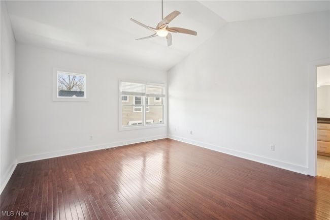 Empty room with vaulted ceiling, wood-type flooring, a ceiling fan, and a wealth of natural light | Image 16