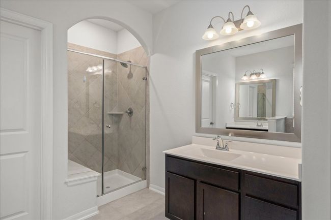 Primary bath featuring a walk in shower with bench, vanity, and tile patterned flooring | Image 26