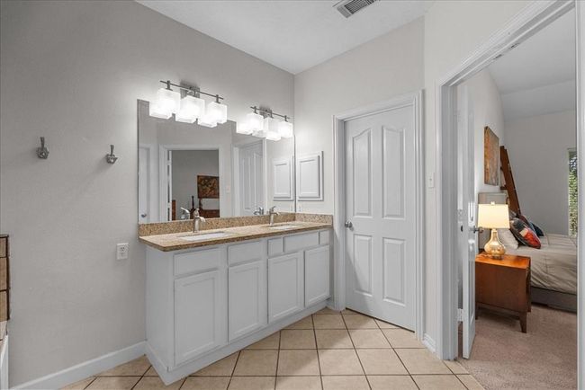 This primary bath features a spacious layout with a walk-in shower, a large soaking tub, dual sinks with granite countertops, and modern light fixtures. | Image 20