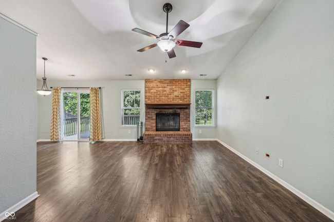 unfurnished living room featuring a ceiling fan, dark wood-type flooring, and a fireplace | Image 8