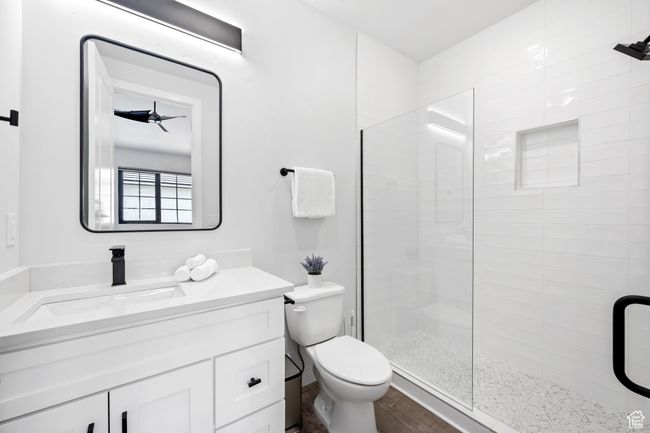 Bathroom featuring toilet, a shower with shower door, ceiling fan, wood-type flooring, and vanity | Image 17