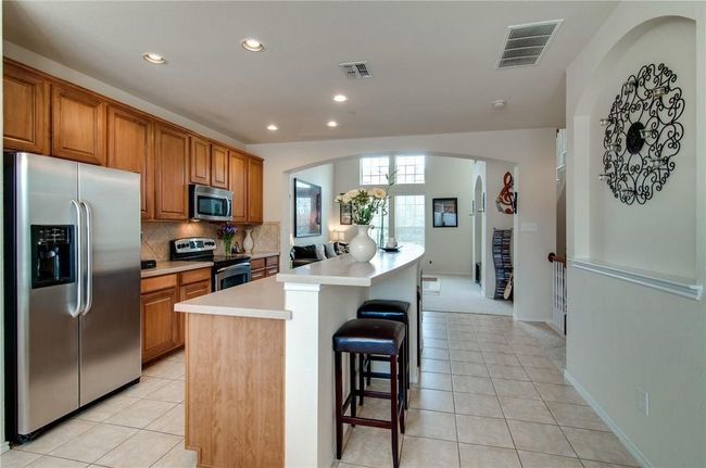 Kitchen with tasteful backsplash, light tile patterned flooring, a center island, and appliances with stainless steel finishes | Image 10