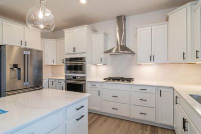 Photo is of the actual home. The spacious gourmet kitchen features a large center island, quartz countertops, LVP floors, stainless appliances and more! | Image 2