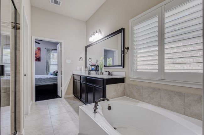 Ensuite bathroom featuring a garden tub, vanity, tile patterned floors, baseboards, and a shower with door | Image 27