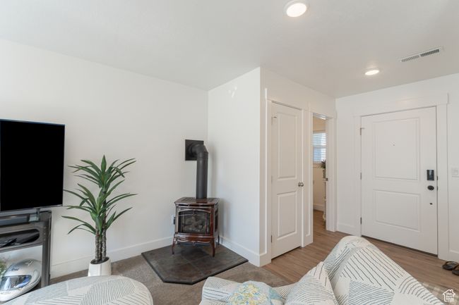 Living room with baseboards, recessed lighting, a wood stove, visible vents, and wood finished floors | Image 5