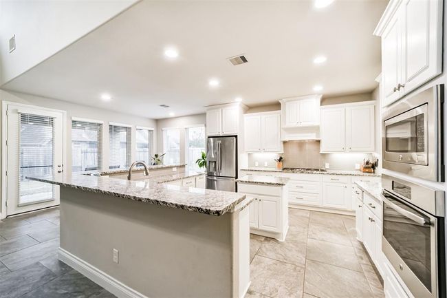 This oversized chef's style kitchen is perfect for entertaining. Ample counter & cabinet space along with a gas cooktop, convection oven and microwave. Nice details in the designer back splash and undercabinet lighting . | Image 5