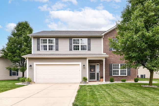 traditional-style home featuring a garage, driveway, a front lawn, and brick siding | Image 4