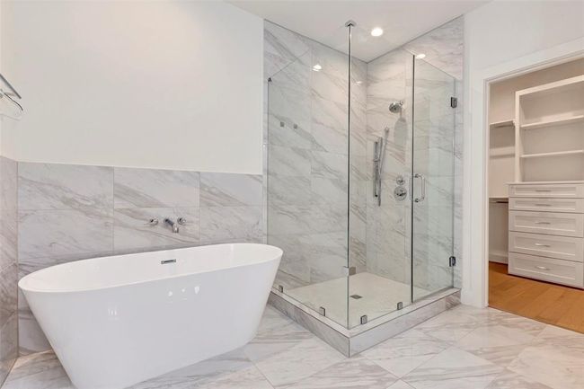 The primary bathroom features a shower elegantly enclosed by glass and a separate contemporary tub. | Image 18