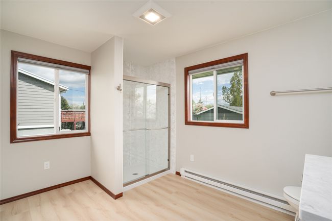 Bathroom with a baseboard radiator, wood finished floors, a stall shower, toilet, and baseboards | Image 19