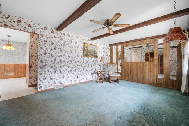 Empty room featuring wallpapered walls, visible vents, a ceiling fan, carpet, and beam ceiling | Image 6