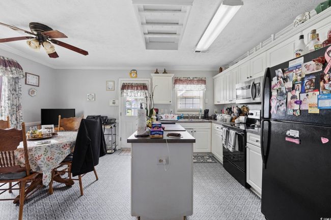 Kitchen featuring black appliances, a center island, white cabinets, crown molding, and a textured ceiling | Image 6