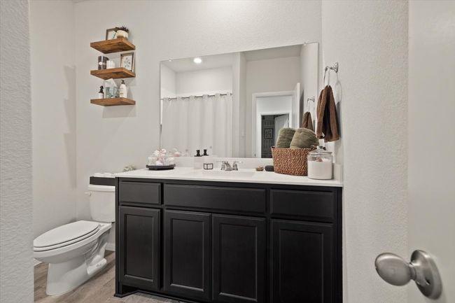 Bathroom with toilet, wood finished floors, vanity, a textured wall, and a shower with curtain | Image 26