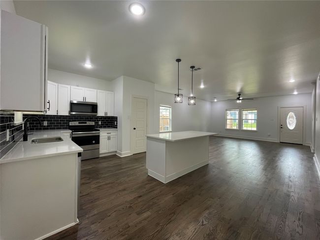 Kitchen featuring a sink, appliances with stainless steel finishes, a center island, dark wood-type flooring, and a ceiling fan | Image 14