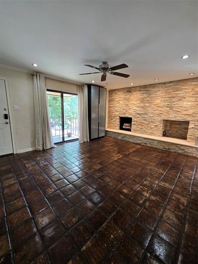 Unfurnished living room featuring dark tile patterned floors, a fireplace, and ceiling fan | Image 3