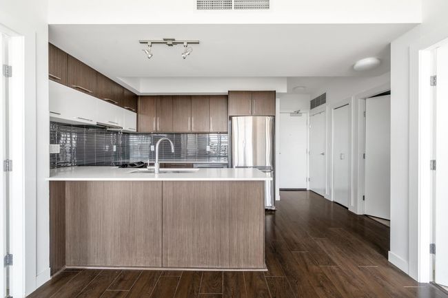 Kitchen featuring freestanding refrigerator, a peninsula, light countertops, dark wood-style floors, and decorative backsplash | Image 11