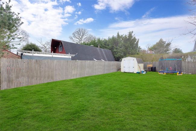 View of yard with a storage shed, a trampoline, a fenced backyard, and an outdoor structure | Image 18
