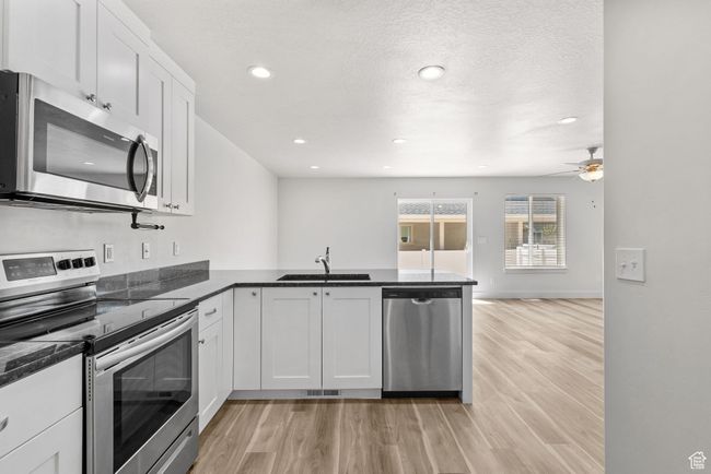 Kitchen with stainless steel appliances, a sink, a peninsula, light wood-style flooring, and recessed lighting | Image 11