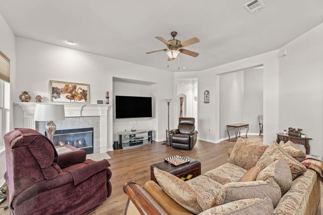 Living area featuring a ceiling fan, a fireplace, wood finished floors, and arched walkways | Image 14