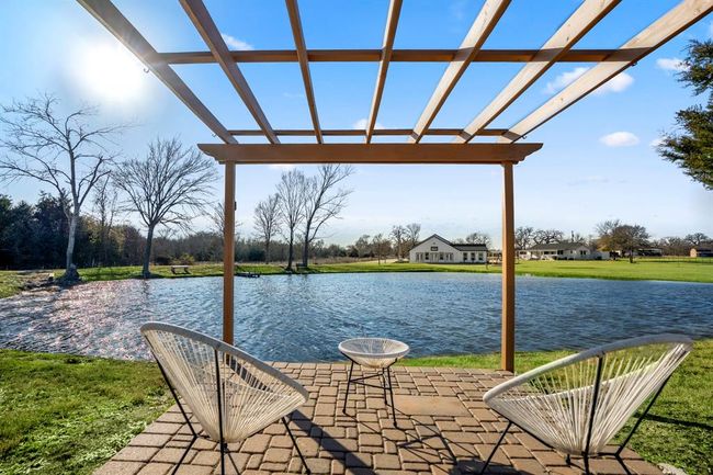 A pergola-covered seating area by the pond offers a peaceful place to take in the views and enjoy the outdoors. | Image 39